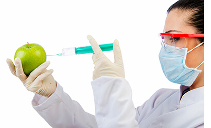 Female scientist performing a Chemical experiment with an apple by injecting it